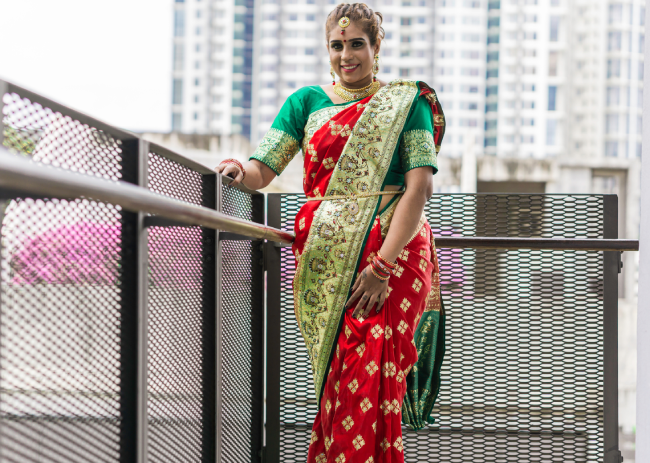 A woman is wearing beautiful jewellery and a rich saree.